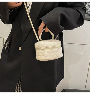 Detail of white quilted leather mini vanity bag with gold chain strap on black blazer