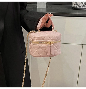 Detail of pink quilted mini crossbody bag with gold-tone hardware and chain strap