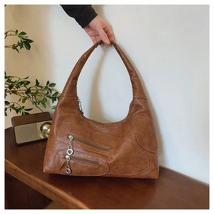 Detailed view of a vintage brown nylon handbag with dual zippers and metal charms