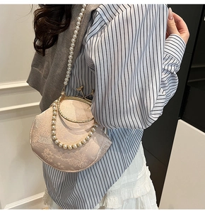 Detail view of beige shell bag with floral embroidery and pearl chain straps
