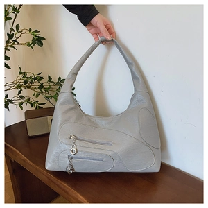 Detail of grey vintage nylon shoulder bag with silver zippers on a wooden stool