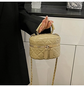 Detail of a mini cylindrical handbag with quilted stitching and gold chain strap