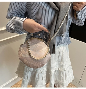 Detail of elegant floral jacquard shell bag with pearl strap and metal handle
