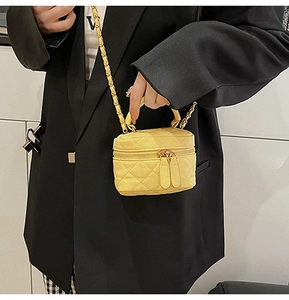 Close-up of vibrant yellow quilted mini bag with gold chain strap and dual zippers