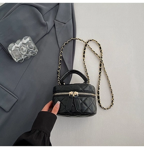 Detail of mini quilted black crossbody bag with gold zippers and chain strap