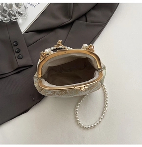 Close-up of bird clasp and pearl chain on a floral jacquard shell evening bag