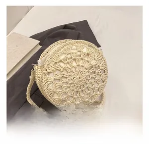 Detail of round straw crossbody bag featuring hollow radial weave and zip closure
