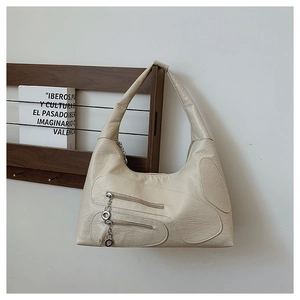 Detail of retro cream nylon shoulder bag featuring textured fabric and silver metal charms