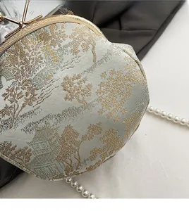 Detailed close-up of vintage jacquard fabric and pearl chain on a shell clutch bag