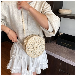 Detail of a beige crochet straw crossbody bag with radial cutouts and woven strap