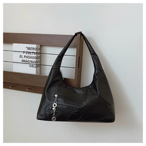 Detail of black nylon shoulder bag with decorative silver zippers and chain accessory