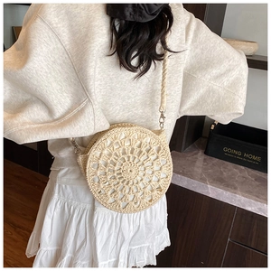 Detail of beige crochet straw crossbody bag with floral pattern and woven shoulder strap