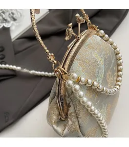 Detail of vintage evening shell bag with carved gold handles and pearl strap decoration