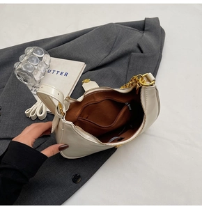 Detail view of cream crescent bag featuring a gold zipper and brown fabric lining