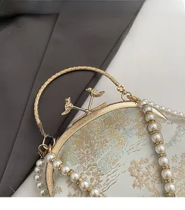 Detail of vintage bird-shaped metal clasp and pearl handle on floral embroidery bag