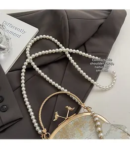 Detail of floral jacquard shell bag with pearl strap and golden bird handle ornament