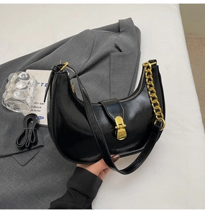 Detail of black crescent hobo bag with gold metal buckle and chunky chain strap