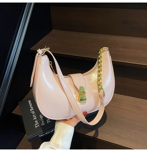 Detail of light pink hobo bag featuring glossy faux leather and a bold gold chain strap