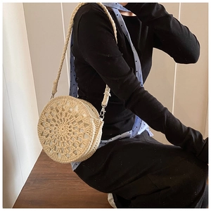 Detail of bohemian handmade straw bag featuring a radial woven pattern and silver metal clasp