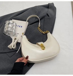 Detail of off-white crescent bag with gold chain strap on grey blazer texture