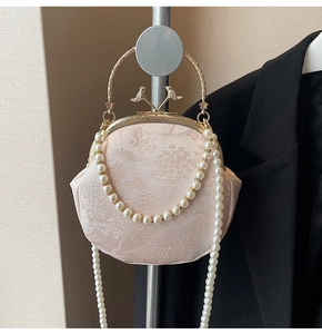 Detail of pink floral embroidery bag with pearl strap and gold metal bird handle