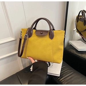 Detail of contrast color tote bag with yellow leather body and chocolate brown handle