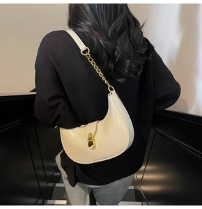 Detail of cream crescent bag with gold chain strap and metallic clasp on model