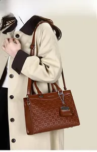Detail view of brown textured tote bag with detachable mini pouch and adjustable strap