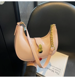 Detailed view of pink crescent hobo bag with gold chain and glossy faux leather finish