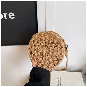 Detail of round straw crossbody bag with radial pattern and metal buckle on strap