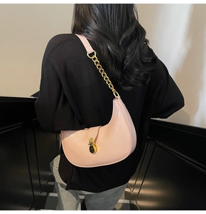 Detailed close-up of a pink crescent bag with shiny finish and golden chain strap