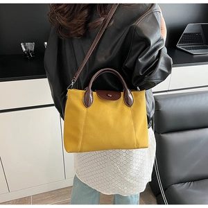 Model view showing the yellow leather handbag with dark brown handles and shoulder strap
