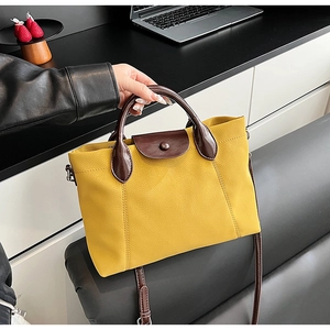 Detail of yellow lychee pattern handbag with brown handles and long shoulder strap