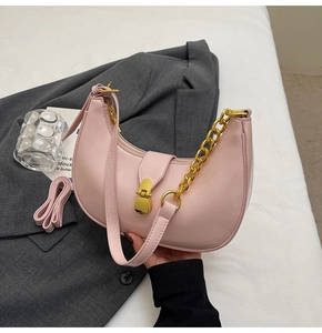 Detailed view of pink crescent bag with gold chain and strap on a gray suit jacket