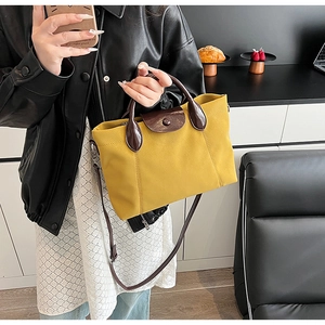 Detail of yellow contrast tote bag showing high-quality leather handles and stitch texture