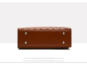 Detailed view of brown tote bag bottom with square embossed pattern and protective metal studs