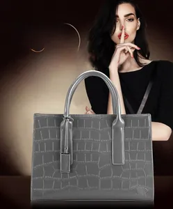 Detailed view of grey crocodile pattern tote bag with dual handles and matching tag