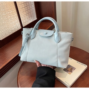 Close-up of light blue leather tote bag with stitch details and adjustable shoulder strap