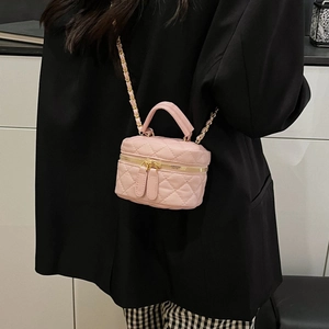 Pink quilted mini vanity bag with gold chain strap shown on model over black suit