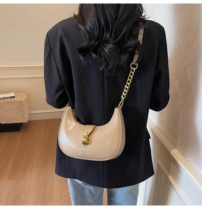 Model view of beige crescent bag with gold chain strap on a black blazer jacket
