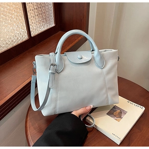 Detail of light blue lychee pattern leather handbag on wood table in a cozy home setting