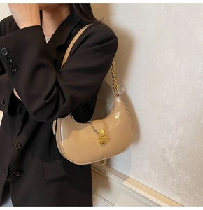 Detailed view of apricot crescent bag with glossy finish and gold metal buckle
