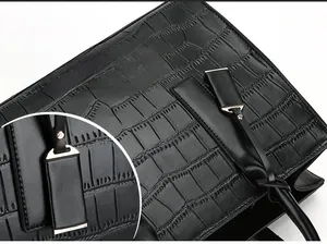 Close-up of black crocodile embossed tote with gold hardware and detailed macro view