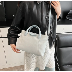 Detail of light blue faux leather tote with snap button flap and silver hardware details