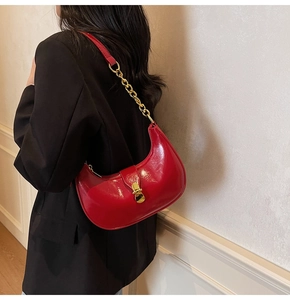 Close-up of a red crescent hobo bag with gold chain strap on a black blazer