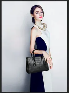 Detail of black crocodile texture tote bag with rounded handles and decorative pendant