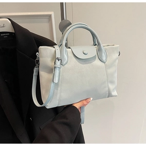 Detail of light blue minimalist leather handbag with adjustable strap and top handle