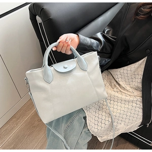 Close-up of light blue lychee pattern leather handbag with circular handles and silver hardware