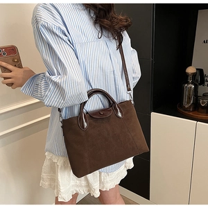 Detail of a deep brown lychee leather tote bag with contrasting dark coffee handles