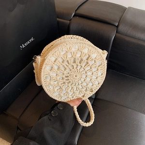 Handmade beige round straw shoulder bag with woven pattern and top handle for beach use